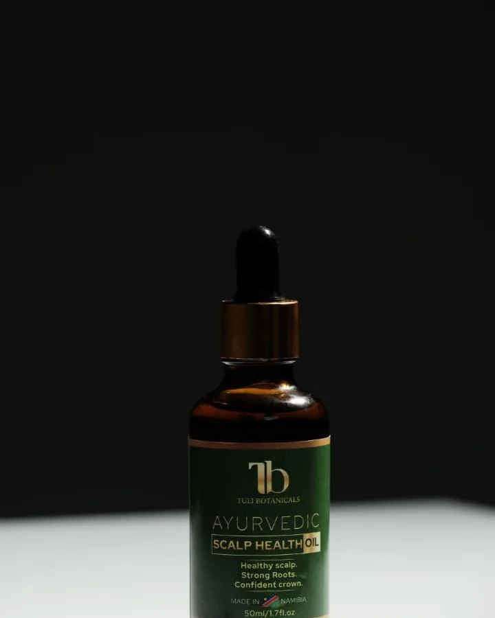 Tuli Botanicals oil bottle standing in a beam of light against a dark wall.